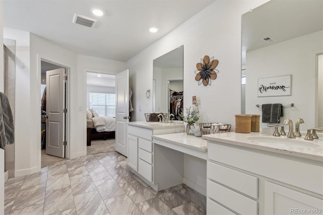 ensuite bathroom with recessed lighting, visible vents, vanity, and a spacious closet