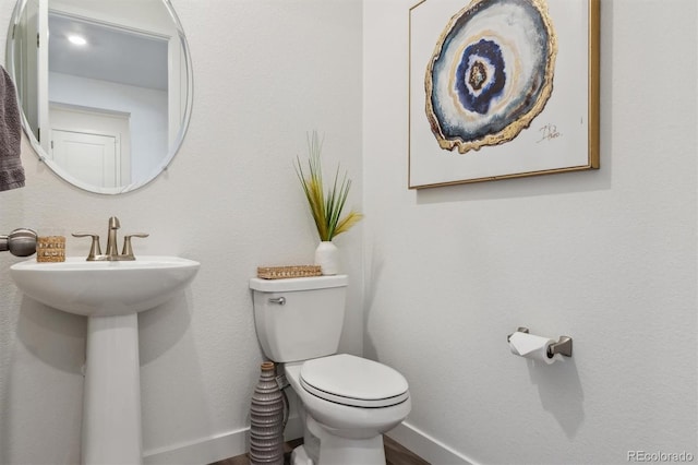 bathroom featuring toilet, baseboards, and a sink