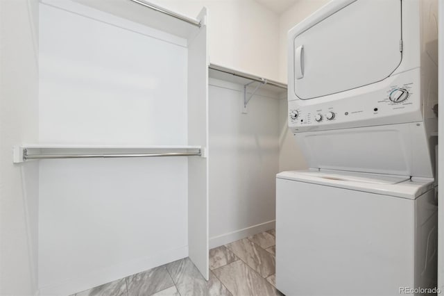 laundry area with laundry area, stacked washer and dryer, and baseboards