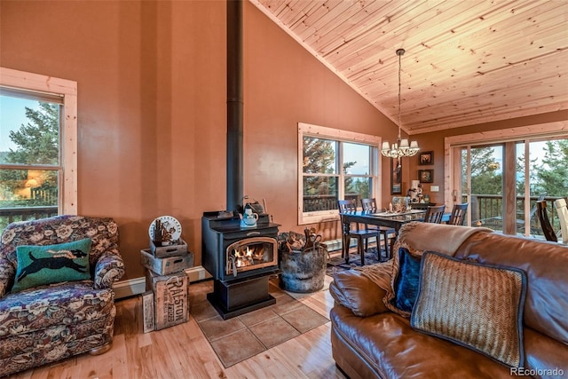 living room with high vaulted ceiling, wood ceiling, a wood stove, and light wood finished floors