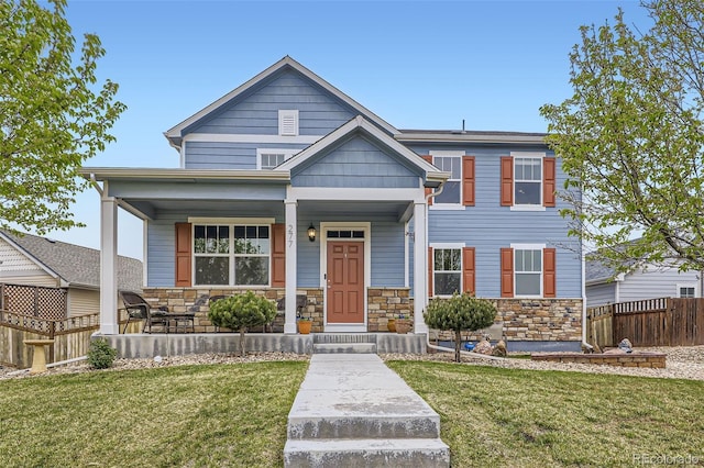 277 Jewel St, Brighton, CO 80603 - view of front facade featuring a porch, fence, stone siding, and a front lawn