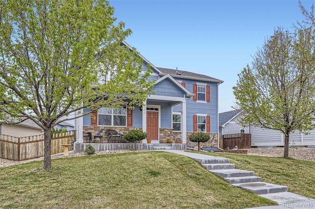 277 Jewel St, Brighton, CO 80603 - view of front facade featuring covered porch, fence, stone siding, and a front lawn