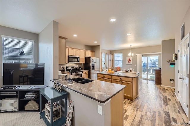 277 Jewel St, Brighton, CO 80603 - kitchen with light brown cabinetry, appliances with stainless steel finishes, a sink, a peninsula, and light wood-style flooring