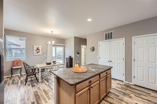277 Jewel St, Brighton, CO 80603 - kitchen with visible vents, a center island, dark stone countertops, recessed lighting, and light wood-style flooring