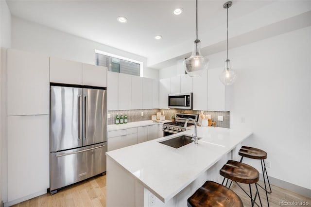 3008 Blake St, Denver, CO 80205 - kitchen with high quality appliances, a kitchen bar, a peninsula, light wood finished floors, and recessed lighting