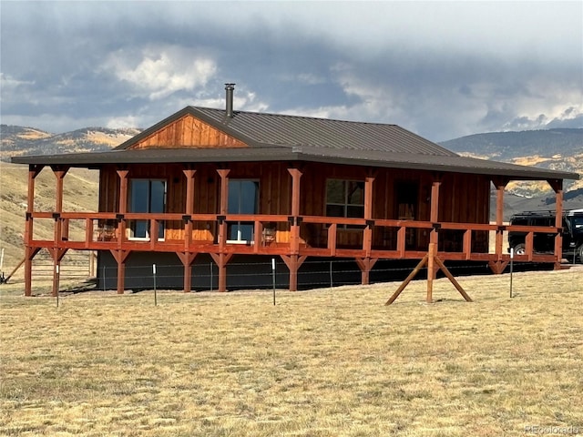 back of house with a mountain view and a lawn