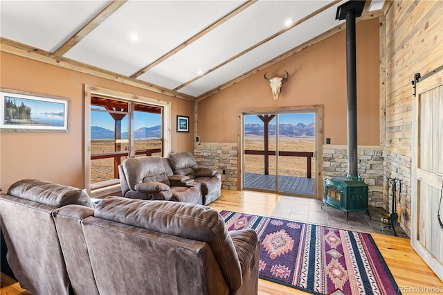 living room with a wood stove, lofted ceiling with beams, a mountain view, and plenty of natural light