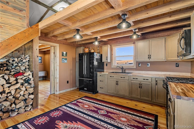 kitchen with black appliances, beamed ceiling, sink, light hardwood / wood-style flooring, and wood counters