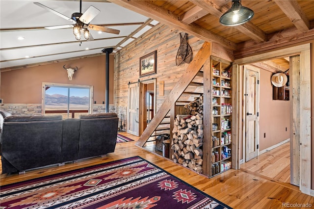 living room with light hardwood / wood-style floors, wood ceiling, beamed ceiling, and a wood stove