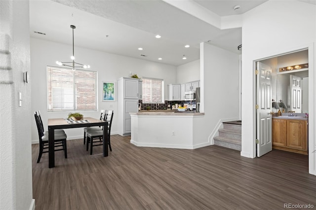 kitchen with tasteful backsplash, dark hardwood / wood-style flooring, kitchen peninsula, and white cabinets