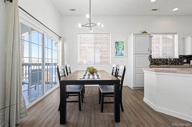 dining room featuring an inviting chandelier, a wealth of natural light, and dark hardwood / wood-style flooring