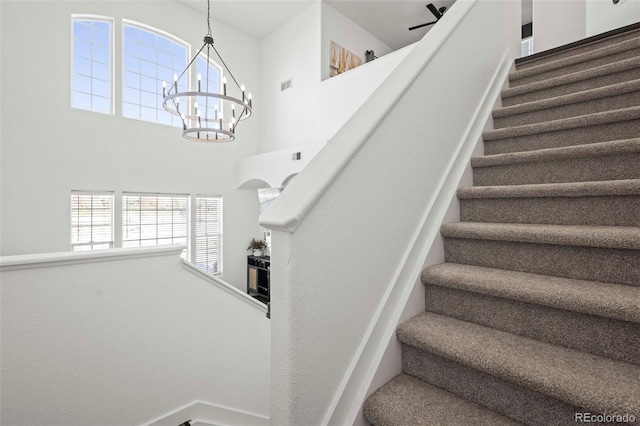 staircase with a high ceiling and a chandelier