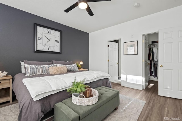 bedroom with a spacious closet, a closet, ceiling fan, and hardwood / wood-style flooring