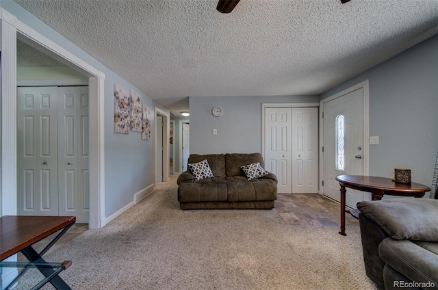 carpeted living room featuring ceiling fan and a textured ceiling