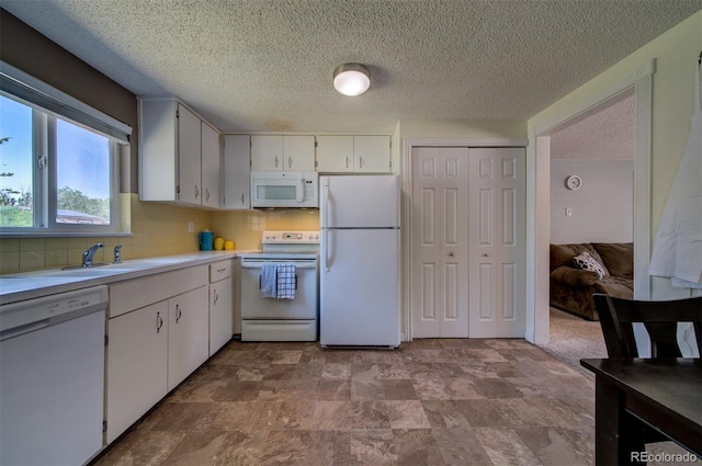 kitchen with a textured ceiling, white appliances, white cabinets, tasteful backsplash, and carpet