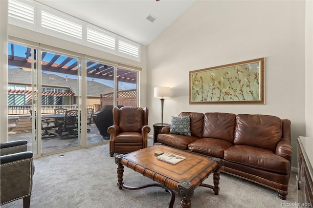 carpeted living area with high vaulted ceiling and visible vents