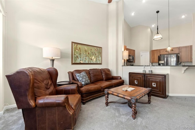 living area with baseboards, high vaulted ceiling, and light colored carpet