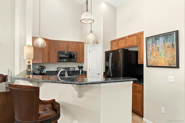 kitchen featuring stainless steel appliances, brown cabinetry, decorative light fixtures, and a kitchen bar