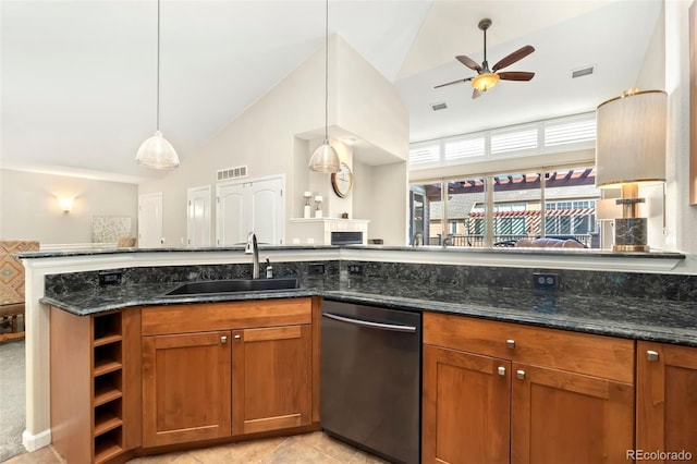 kitchen featuring dark stone counters, decorative light fixtures, dishwasher, and a sink