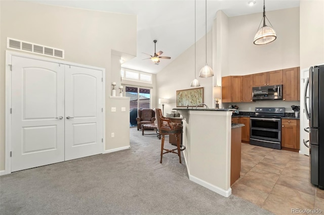 kitchen with stainless steel appliances, a breakfast bar, visible vents, dark countertops, and decorative light fixtures