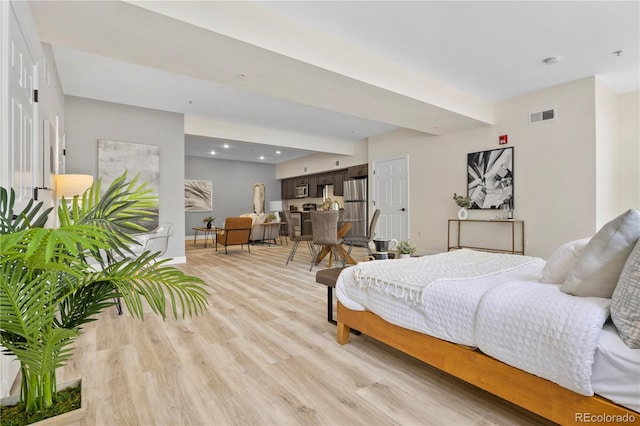 bedroom featuring light hardwood / wood-style floors and stainless steel refrigerator