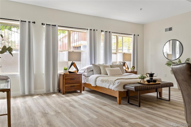 bedroom with light hardwood / wood-style floors and multiple windows