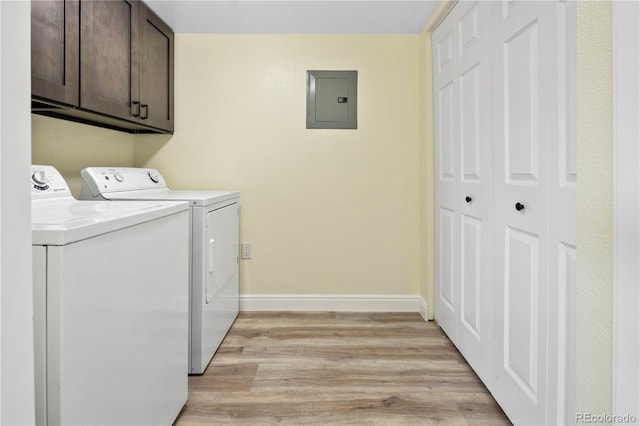 laundry room with cabinets, electric panel, washer and clothes dryer, and light wood-type flooring