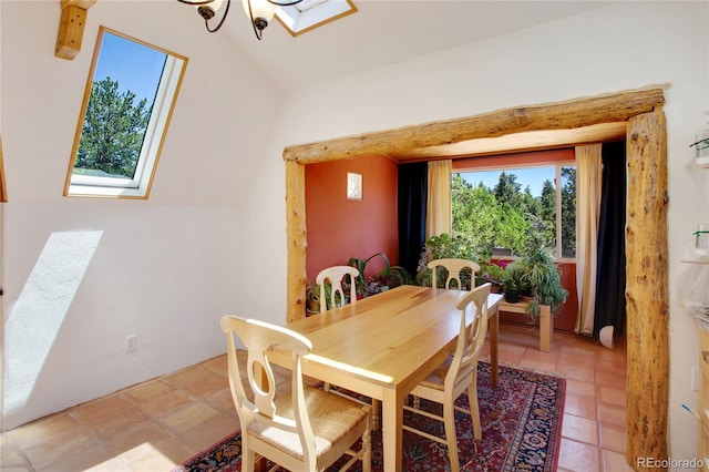 dining room with an inviting chandelier, tile floors, and lofted ceiling with skylight