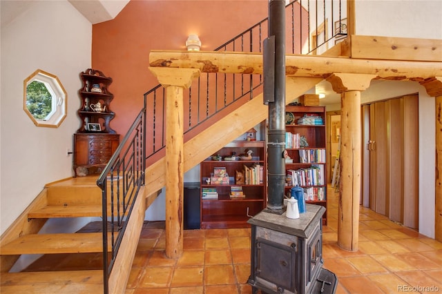 stairway with a towering ceiling, tile flooring, and a wood stove