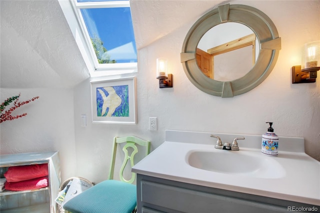 bathroom with lofted ceiling with skylight and vanity