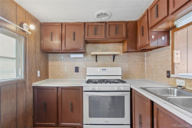 kitchen with tasteful backsplash, sink, and white range with gas stovetop