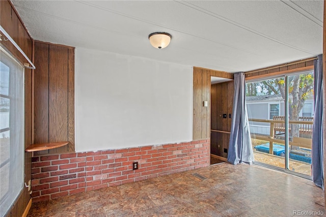 unfurnished room featuring a textured ceiling and wooden walls