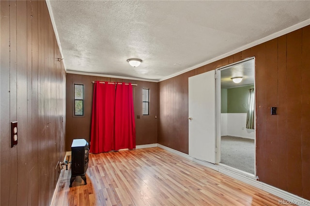 unfurnished room with ornamental molding, light hardwood / wood-style flooring, and wood walls