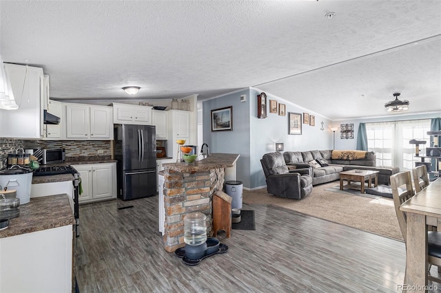 kitchen with dark wood-style flooring, white cabinetry, open floor plan, freestanding refrigerator, and dark countertops