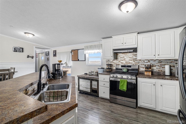 kitchen featuring dark countertops, stainless steel gas range, under cabinet range hood, and a sink