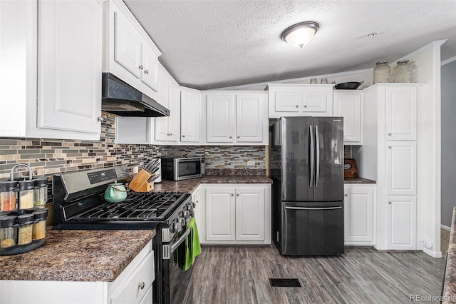 kitchen featuring under cabinet range hood, stainless steel appliances, wood finished floors, white cabinets, and dark countertops