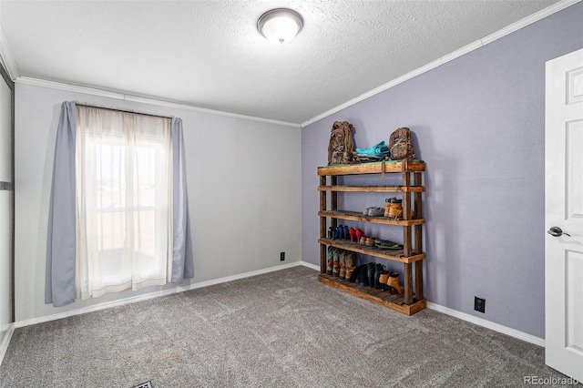 carpeted empty room with a textured ceiling, baseboards, and crown molding