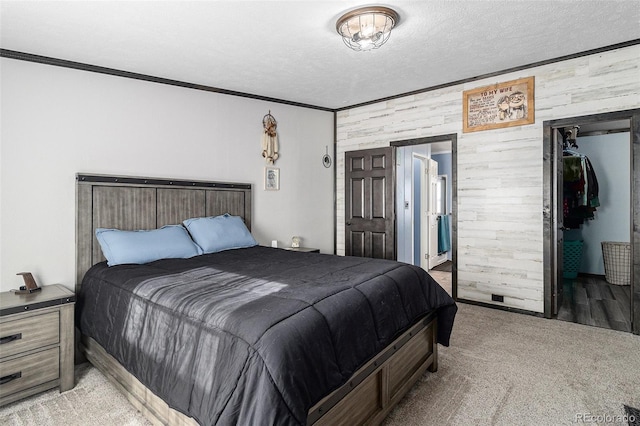 bedroom featuring a textured ceiling, light carpet, wood walls, ornamental molding, and a closet