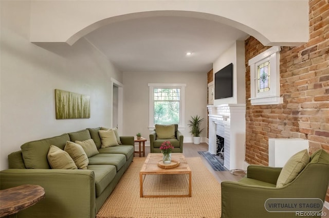 575 N Marion St, Denver, CO 80218 - living room featuring arched walkways, a fireplace with flush hearth, brick wall, and wood finished floors