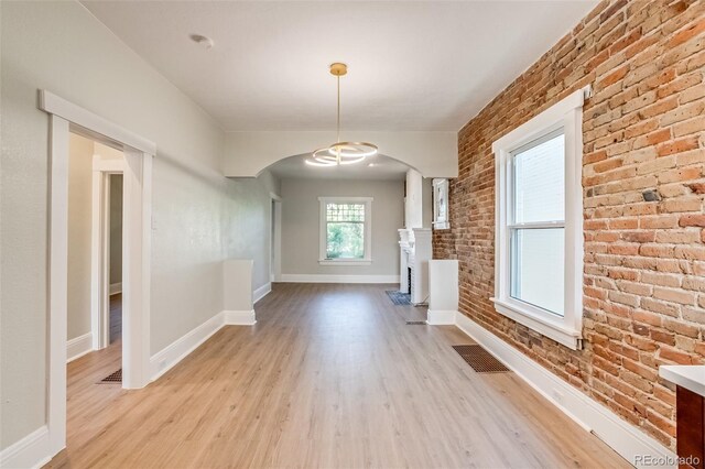 575 N Marion St, Denver, CO 80218 - unfurnished living room featuring arched walkways, light wood-style flooring, and brick wall