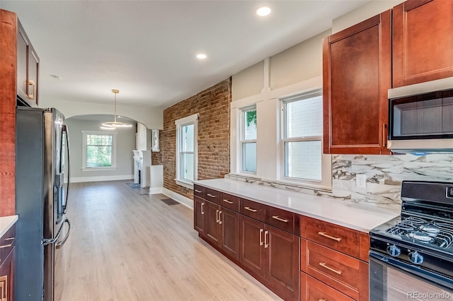 575 N Marion St, Denver, CO 80218 - kitchen with appliances with stainless steel finishes, arched walkways, light countertops, light wood-style flooring, and brick wall
