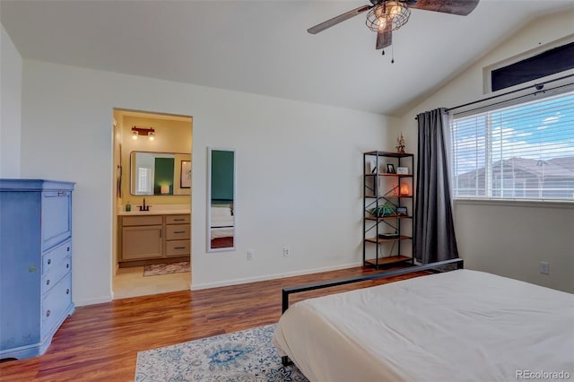 bedroom featuring vaulted ceiling, light hardwood / wood-style flooring, connected bathroom, ceiling fan, and sink