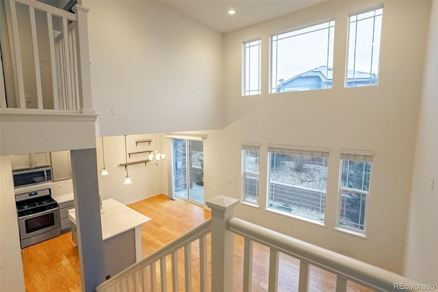 interior space featuring a towering ceiling, light wood-type flooring, and plenty of natural light