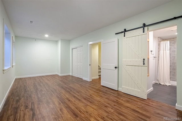 empty room with a barn door and hardwood / wood-style floors