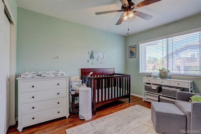 bedroom featuring ceiling fan, light hardwood / wood-style flooring, a closet, and a crib