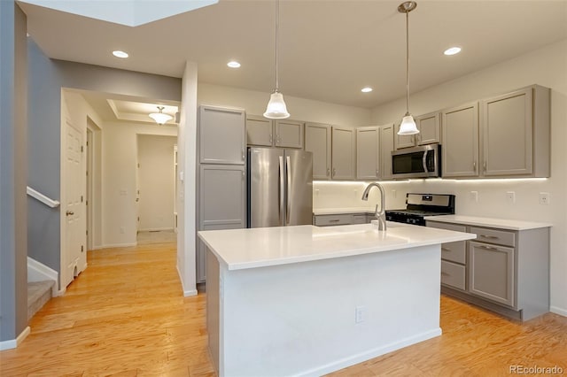 kitchen featuring hanging light fixtures, a center island with sink, gray cabinetry, appliances with stainless steel finishes, and sink