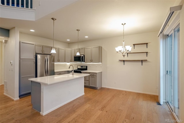 kitchen featuring a kitchen island with sink, gray cabinets, a chandelier, appliances with stainless steel finishes, and light hardwood / wood-style flooring