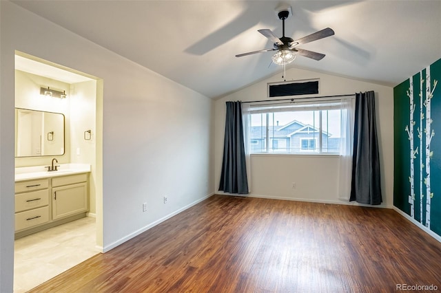 unfurnished bedroom featuring sink, vaulted ceiling, connected bathroom, ceiling fan, and light hardwood / wood-style floors