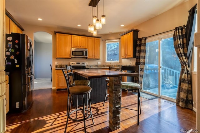 kitchen featuring refrigerator, dark wood-type flooring, sink, decorative light fixtures, and a center island