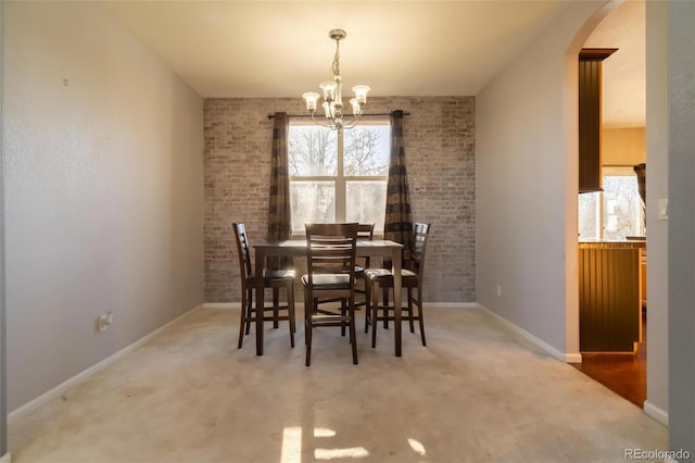 dining room featuring carpet, a chandelier, and brick wall